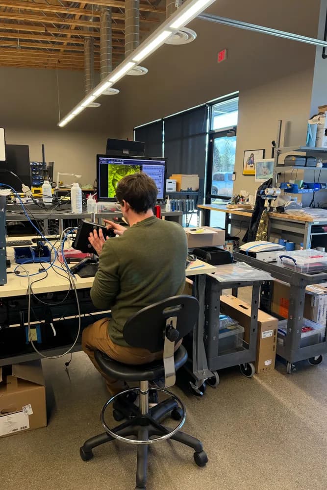 PMI engineer at QC calibration station reviewing MICRON imaging on monitor